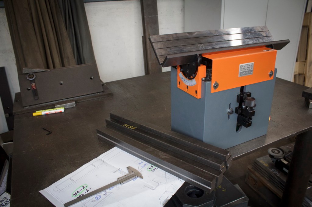 Freesimasin B3 halli ja oranži disainiga, millel on tasane tööpind, reguleeritavad seaded ja täpsuse tagamiseks ümmargune sihverplaat, külgvaates, tööruumis