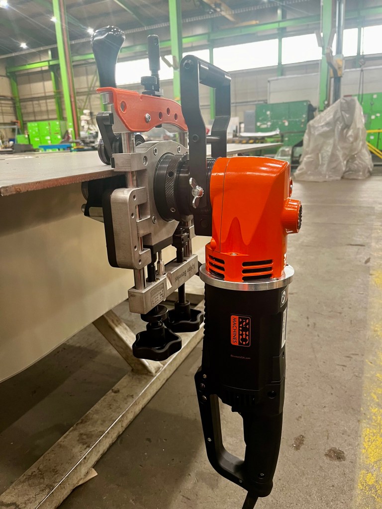 B15 INOX käsitsi faasimismasin oranži-musta disainiga, paigutatud metallpinnale tööstuslikus keskkonnas.